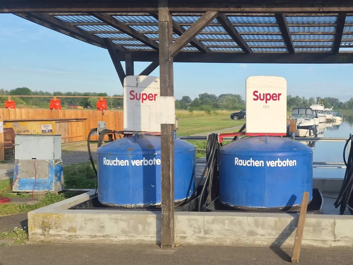 Die Bootstankstelle unter ihrem Vordach: zwei Zapfsäulen auf blauen Tanks am Tanksteg