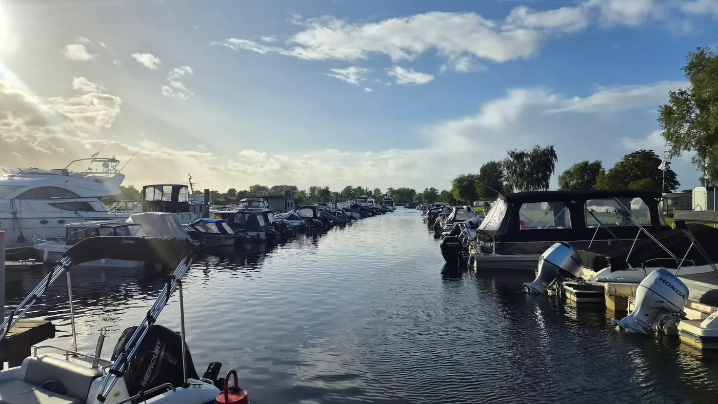 Das Hafenbecken im Gegenlicht, an beiden Seiten liegen Boote dicht an dicht am Steg