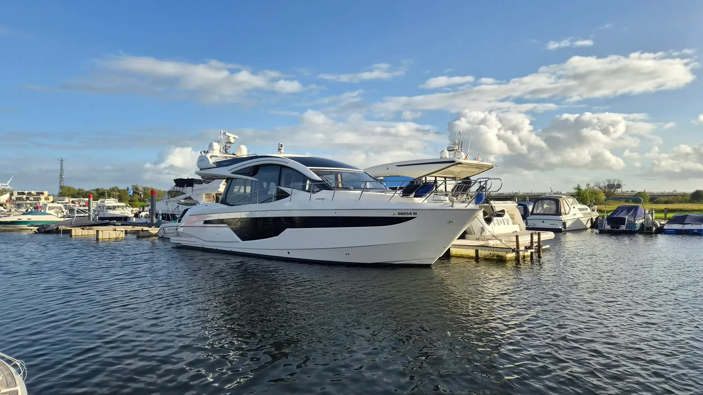 Eine große weiße Motoryacht liegt am Steg im Hafenbecken und spiegelt sich im ruhigen Wasser