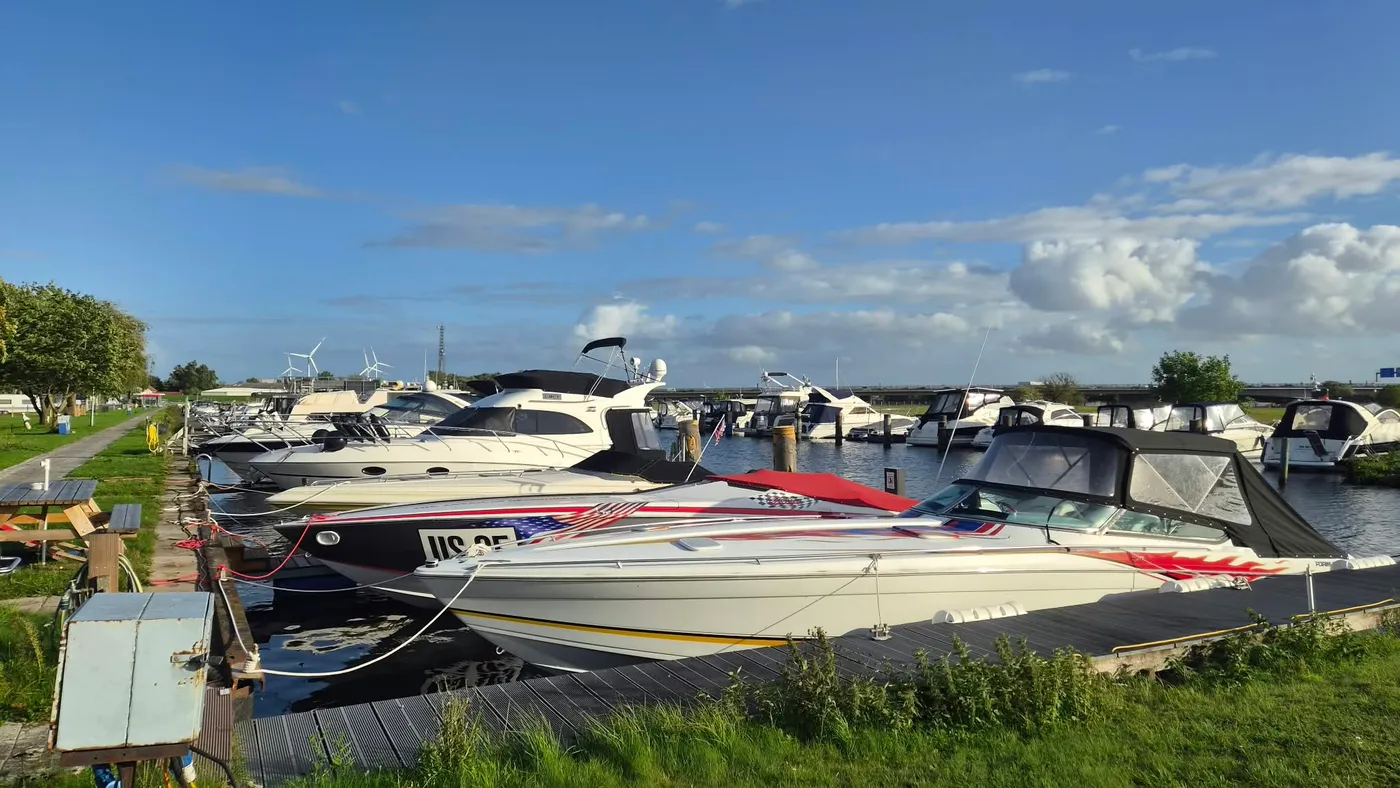 Ein flaches Rennboot mit Sternenbanner-Lackierung liegt vor den Motoryachten am Steg