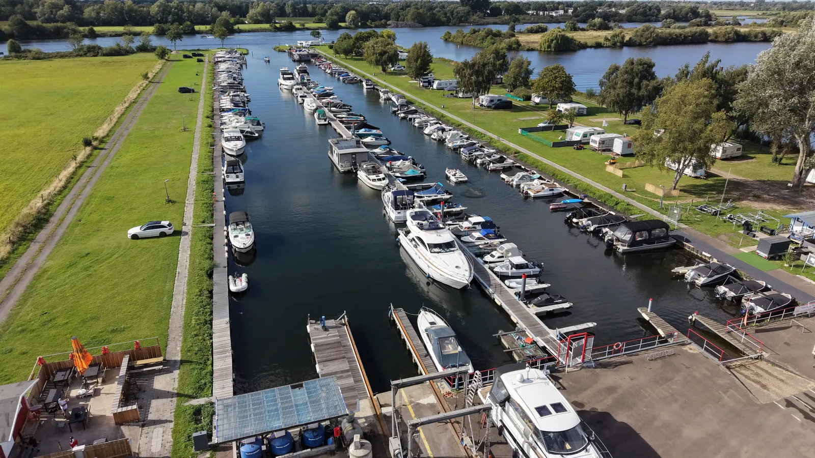 Sportboot im Hafenlift über der Slippbahn, daneben eine Yacht auf dem Trailer